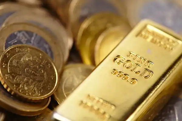 Gold bullion coins arranged beside stacked gold bars